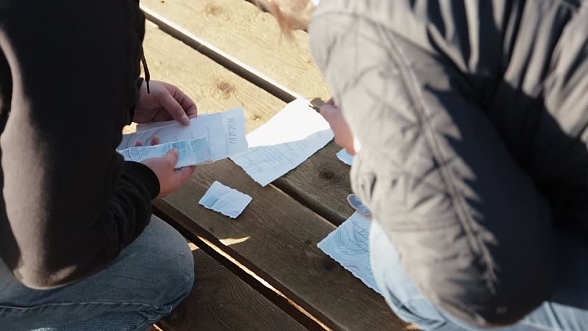 People lay out wedding poligraphic cards at wooden desk floor