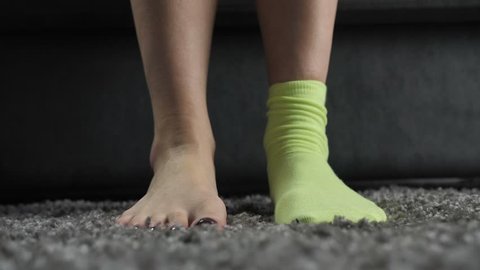 Close-up of woman's hands putting on mismatched socks of different color on her feet. Woman wearing different colored socks on the carpet. Uniqueness, difference and independance concept. Front view