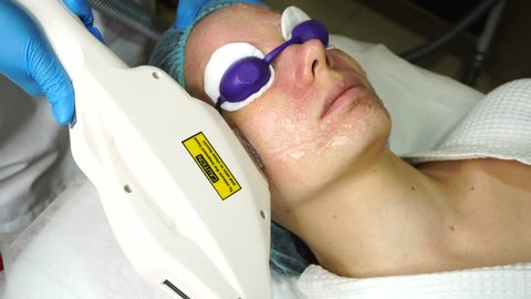 Shooting process nonsurgical facelift. A girl in a spa salon lies on a couch. Facelift device makes flashes