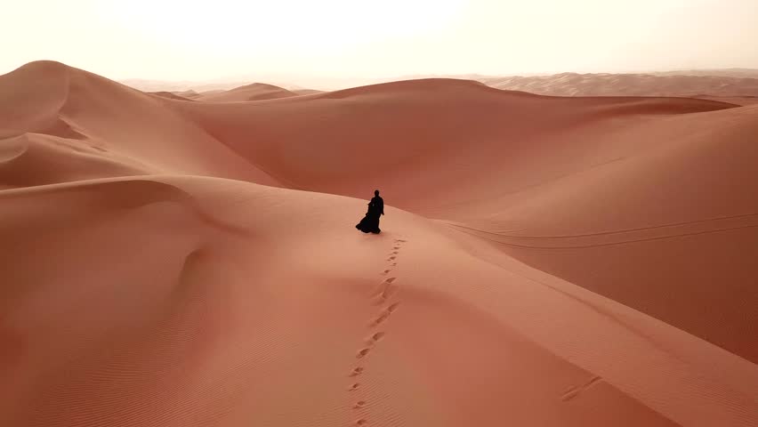 Young beautiful Caucasian woman walking in a traditional Emirati dress - abaya in Empty Quarter desert landscape. Abu Dhabi, UAE. Royalty-Free Stock Footage #1008054994