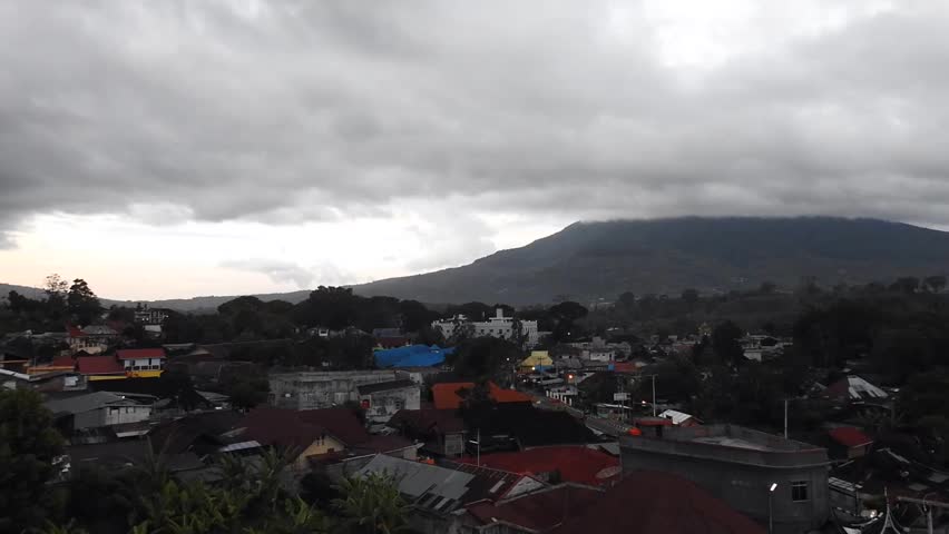 Time lapse : aerial view of mountain at background with motion clouds over the Bukit Tinggi town in morning sunlight