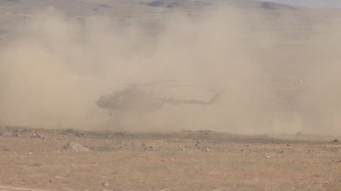 Military paratroopers jump out of a landing helicopter, conduct a special operation in the desert, dust and sand, contour lighting, a general plan.