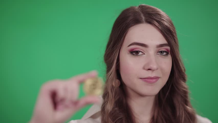 Girl holds a bitcoin coin in her hand, on chroma key background, cryptocurrency, blurred.
