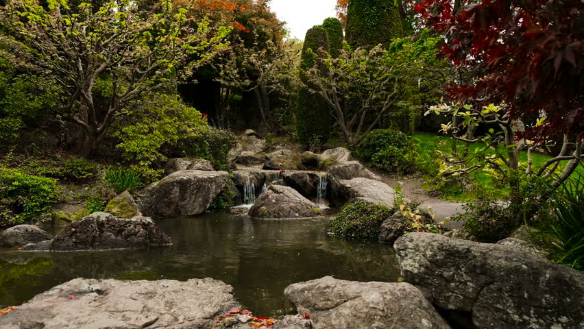 Serenity In Japan Garden, Pond Bordering By Boulders and Autumnal Trees