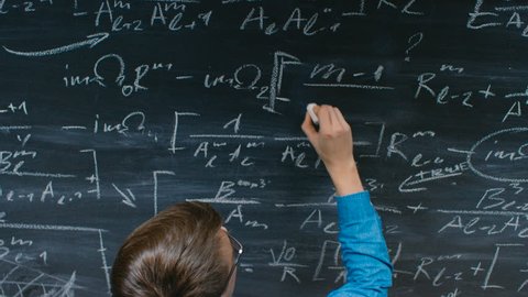 High-Angle Shot of a Brilliant Young Student Writing Big Sophisticated Mathematical Formula/ Equation on the Blackboard. Shot on RED EPIC-W 8K Helium Cinema Camera.