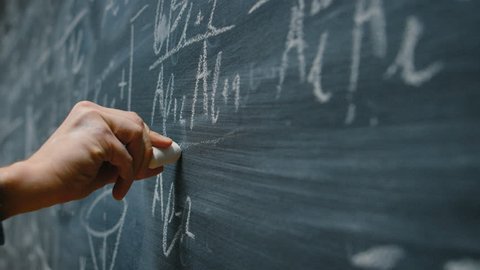 Hand Holding Chalk and Writing Complex and Sophisticated Mathematical Formula Equation on the Blackboard. Shot on RED EPIC-W 8K Helium Cinema Camera.