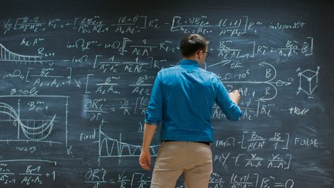 Brilliant Young Mathematician Approaches Big Blackboard and Thinks about Solving Long and Complex Equation/ Formula. Shot on RED EPIC-W 8K Helium Cinema Camera.
