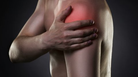 Cinemagraph:  Man with pain in shoulder on black background, studio shot with red dot