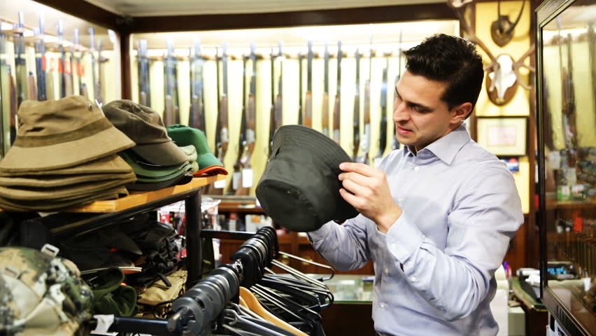 Handsome adult male choosing hunt equipment in store 