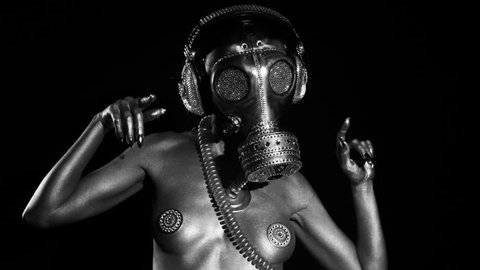 sexy woman dances in silver body paint with a gas mask covered in sparkling crystals. this is a special handmade item from our studio. how to survive the apocalypse in bling bling style