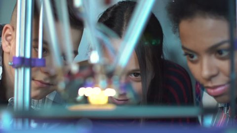 Close view of group of classmates watching after three-dimensional printing in contemporary laboratory. Static 4K shot on Red cinema camera.