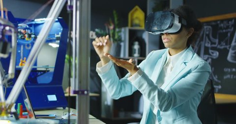 Woman wearing VR headset while working with engineering project in lab with three dimensional printing. Movement 4K shot on Red cinema camera.