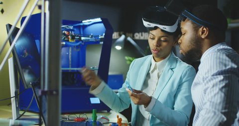 Group of black coworkers in laboratory wearing VR goggles and exploring 3d printing model and check quality of printed product. 4K movement shot on RED cinema camera.