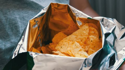 Teenager takes with hands potato chips in packs