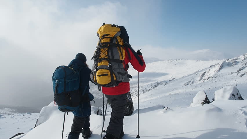 Young Active Successful People Raising Hands On Mountain Top. Hikers Couple with arms raised on top of mountain. Hikers lifting arms up enjoying nature vacation travel adventure. Winter Snow Extreme 