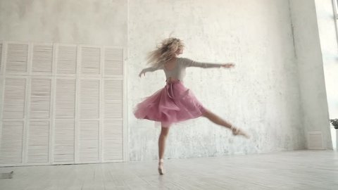 ballet dancer is spinning and jumping high in a tutu and pointe shoes. young ballerina is dancing. slow motion