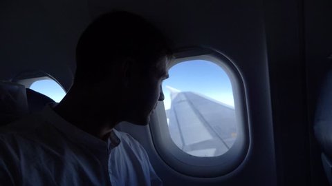 4k, close-up. portrait of a handsome young man who looks at the airplane window during the flight.