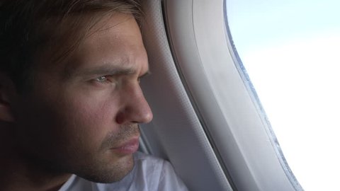 4k, close-up. portrait of a handsome young man who looks at the airplane window during the flight.