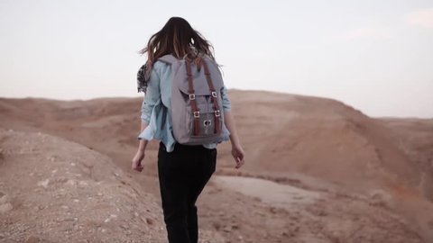 Woman walks near desert canyon. Slow motion. Young woman wanders near sheer drop edge. Rocks and stones. Israel. Freedom