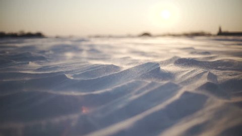 Arctic Storm. Close-up shot of snow storm at sunset. Wind picks snowflakes and carries them across the field