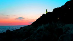 Beautiful Nightly Seascape With a Lighthouse at Sunrise Against a Vibrant Orange - Pink Sky - 4K Video