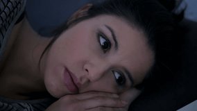 close up video head shot of young attractive hispanic woman upset in stress and insomnia lying anxious on bed trying to sleep suffering sleeping disorder at night looking desperate and frustrated
