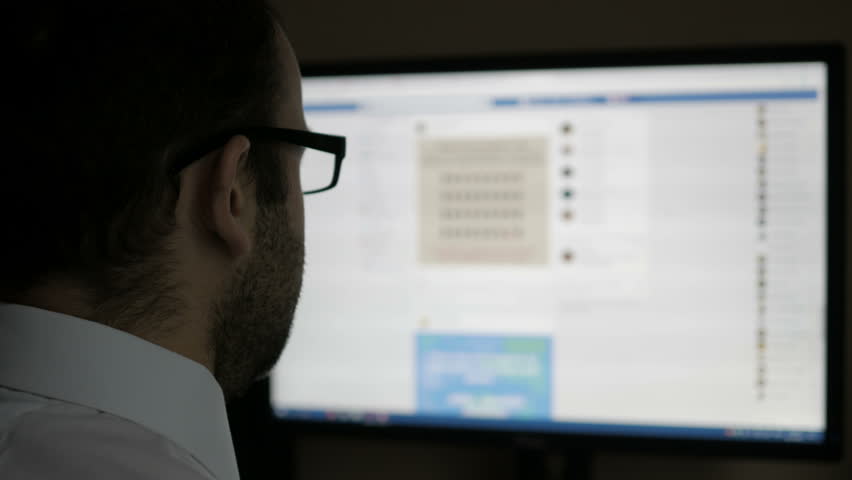 A man using on social networks. Businessman reads the news. Computer monitor showing blur Facebook news feed page online.