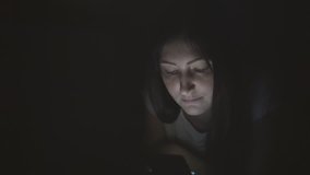 Pretty woman in the dark at night sits with a phone in social networks.
