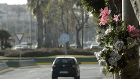 Flowers tied in a street lamp in memory of a traffic accident and cars moving