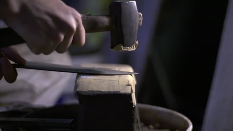 Knife craftsman hammers a traditional Japanese steel blade in workshop. Ancient skills from master sword/katana makers. FS7 with 50MM Ziess.