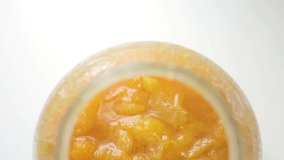 Homemade apricot jam of fresh organic apricots in a jar on a white background. Closeup dolly shot.