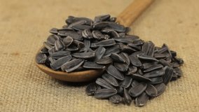 Rotating a spoon, overflowing with sunflower seeds, lying on burlap. - Powered by Shutterstock - Get 15% off with code: PIKWIZARD15