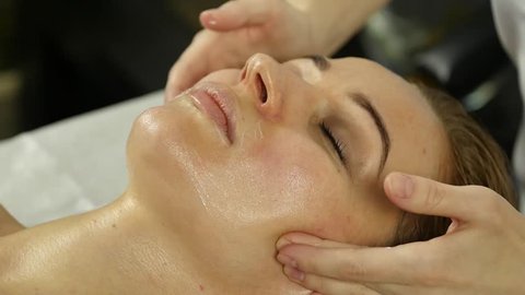 Beautiful woman getting facial massage in spa. facial skin care in beauty saloon. slow motion