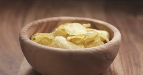Slow motion closeup man hand take potato chip from wood bowl