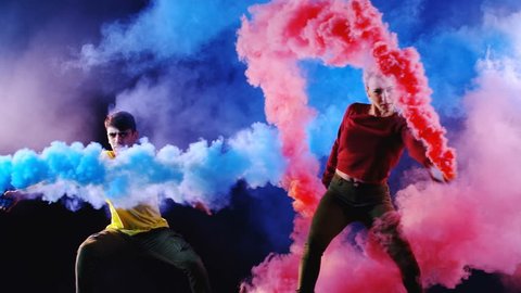 4K Girl and boy are dancing a new style disco contemporary party dance with color smoke grenade in hands. Slow motion (150fps) Shooted on Black Background (high quality)