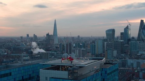 Cinematic aerial of London hospital helipad and London skyline at sunset