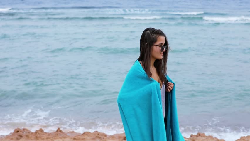 Woman in blue towel standing and relaxing near sea waterfront