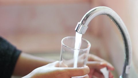 woman hands pouring water from faucet in glass