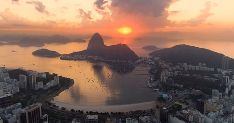 Flying above buildings in Botafogo Bay and Sugarloaf Mountain at sunrise above horizon. Rio de Janeiro, Brazil