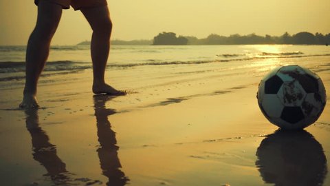 Father and son playing together with ball in football on the beach under sunset background Video Stok