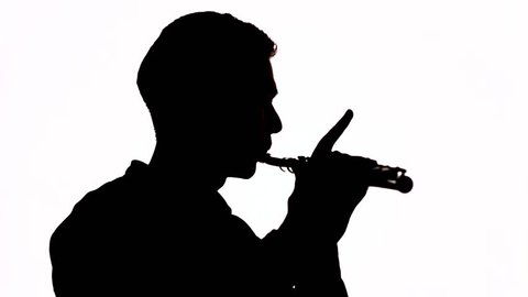 Silhouette. Isolated. The guy plays a beautiful melody on the flute. Profile of the musician. Copy space.