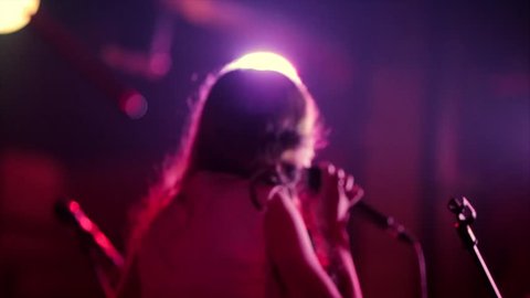 Back view of girl singer in stage lights