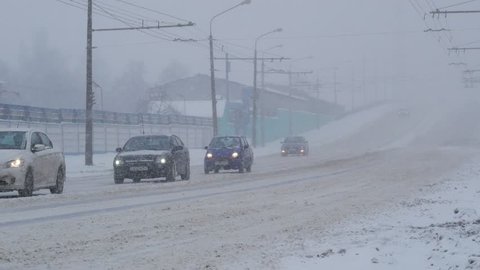 Snow storm in city with blizzard conditions. Traffic driving in the city, during heavy snow storm.