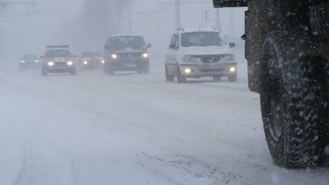 Snow storm in city with blizzard conditions. Traffic driving in the city, during heavy snow storm.