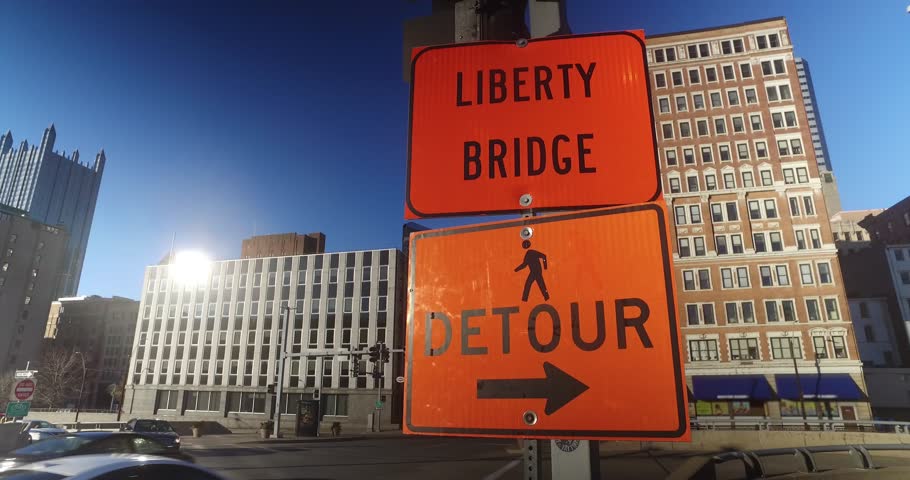 An establishing shot of an orange detour sign in downtown Pittsburgh, Pennsylvania.  	