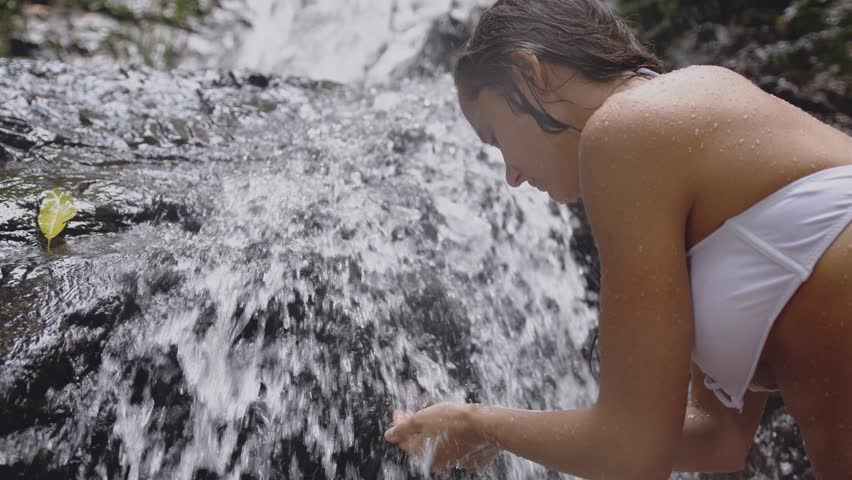 Girl washing her face in a stream of water in a natural waterfall in tropical jungle.slow motion. 3840x2160
