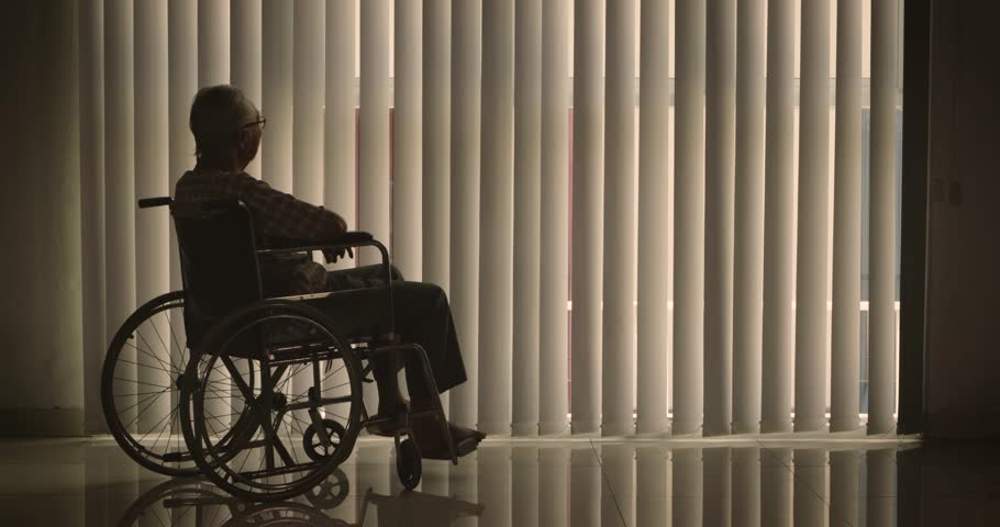 Silhouette of lonely old man sitting on wheelchair while looking at the window with curtain at home. Shot in 4k resolution Royalty-Free Stock Footage #1008185656