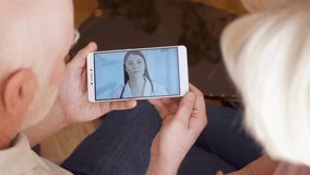 Senior couple at home having medical consultation video chat on mobile with physician. Professional female doctor with stethoscope talking with patients via messenger app call showing drug pills