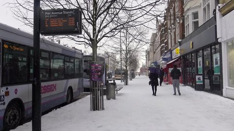 Clacton-on-Sea, England - February 27th 2018 - View of a bus stop and people walking along a street during heavy snowfall.