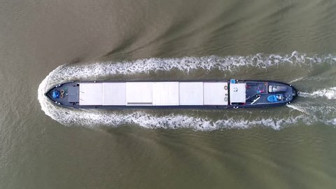 Aerial top down footage of barge moving over canal this flat-bottomed boat is mainly built for river and canal transport of heavy goods most barges are self-propelled steady footage 4k resolution
